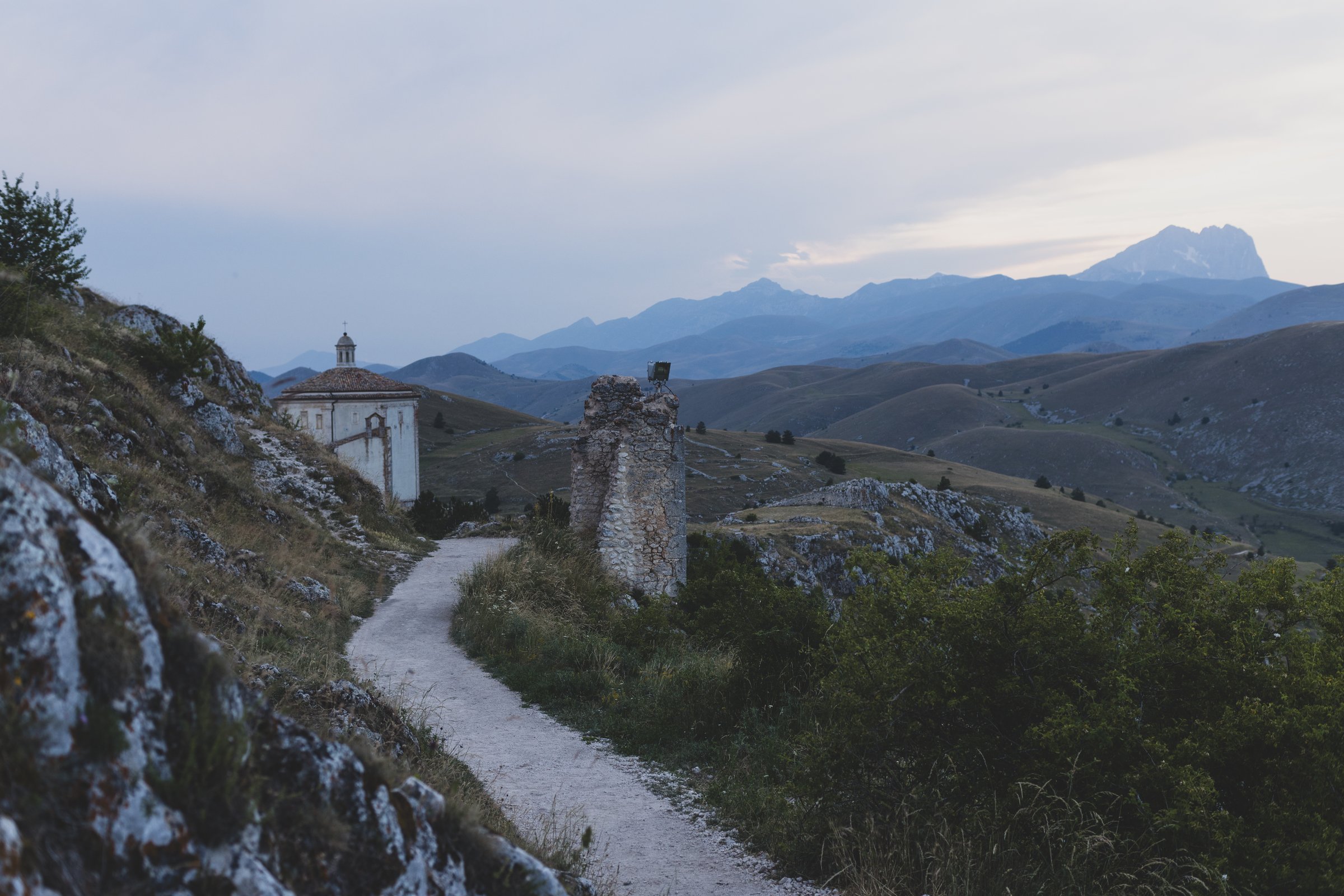 A quiet stone path leading toward a small chapel in the hills above Abruzzo, Italy