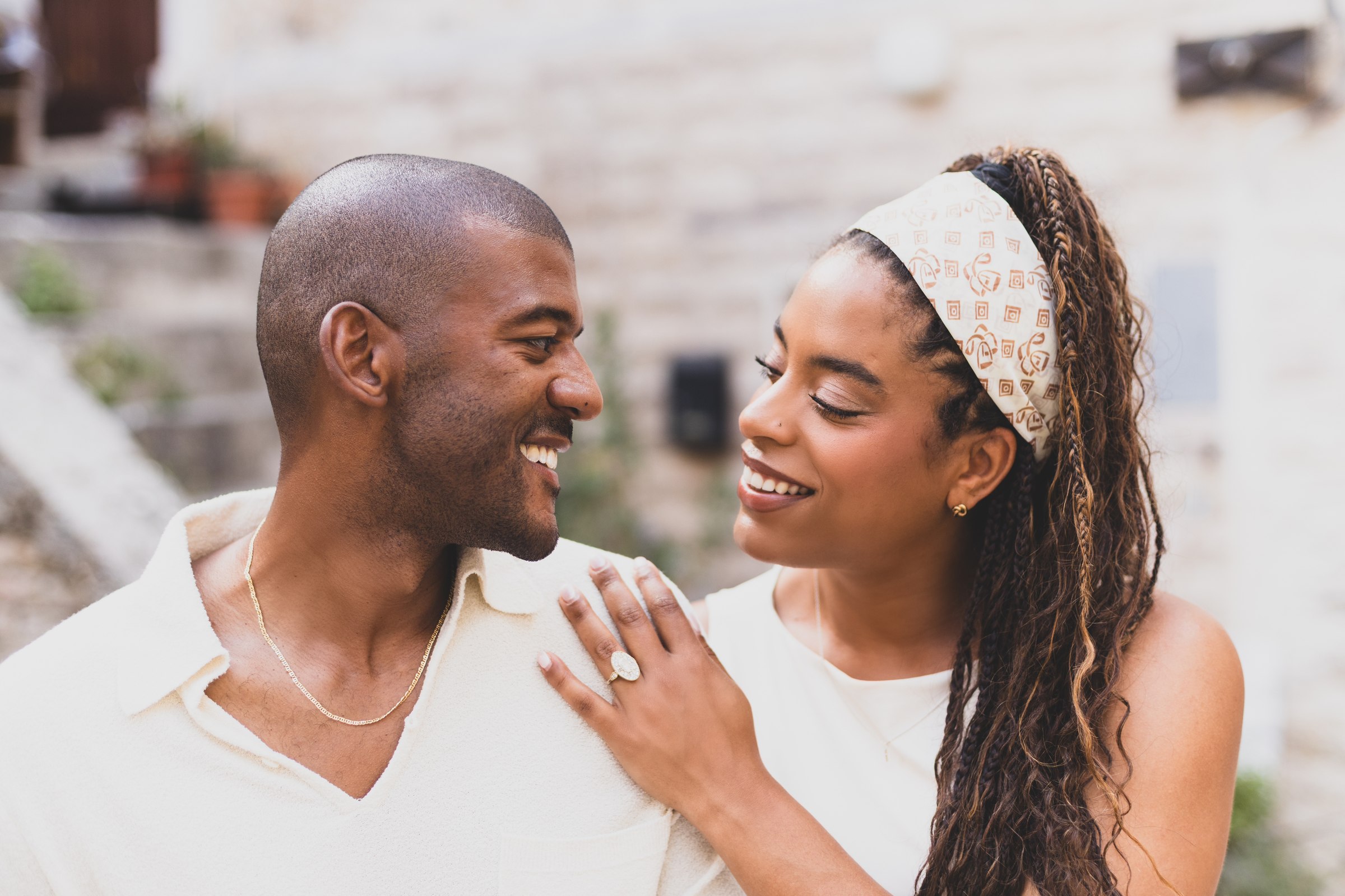 Emily and Nick smiling and holding hands in front of a stone wall in Abruzzo